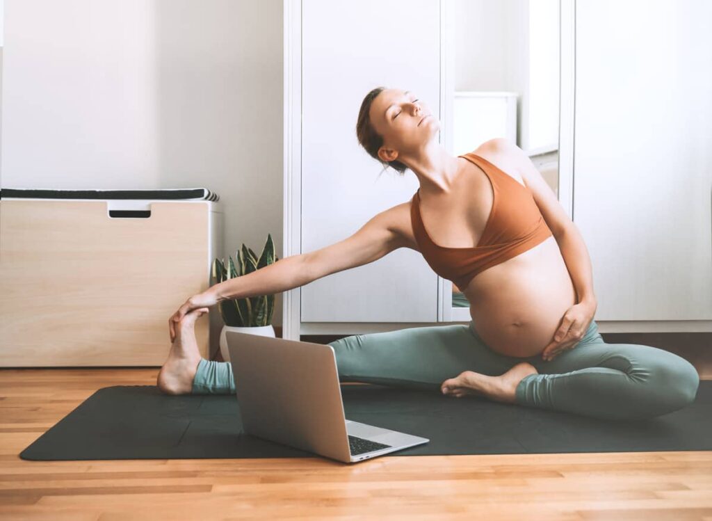 femme enceinte qui fait une séance de yoga chez elle avec des cours en ligne