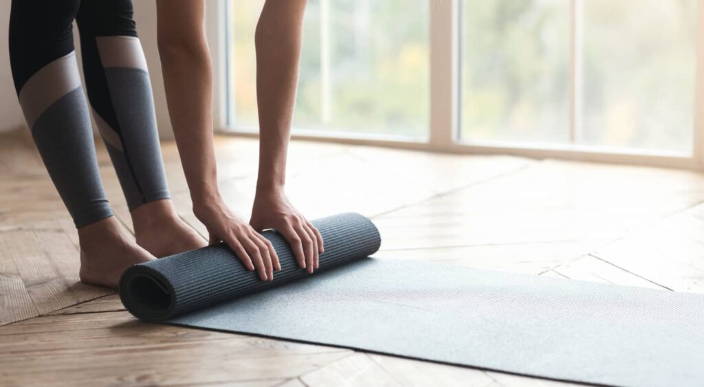 yoga système immunitaire : femme déployant un tapis de yoga