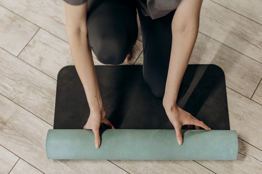 femme qui roule un tapis pour la sophrologie ou yoga