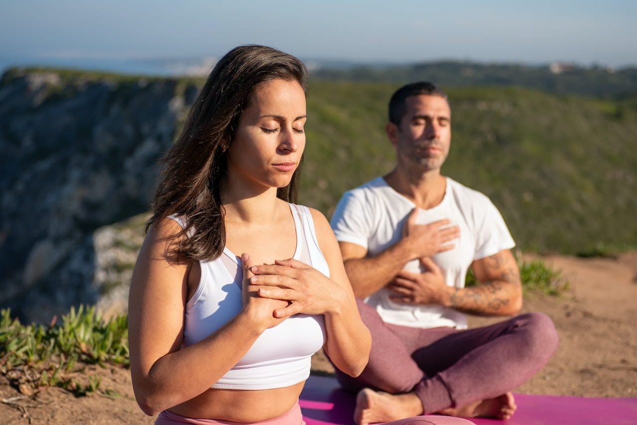 yoga respiration pranayama : un homme et une femme pratiquant un exercice de respiraiton