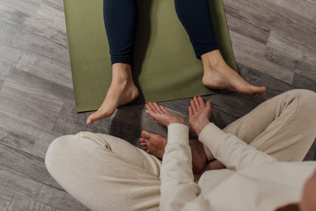 yoga savasana : une instructrice aide le yogi à positionner ses pieds pour la posture du cadavre