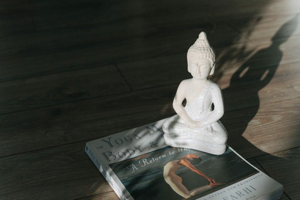 yoga et bouddhisme : une figurine de bouddha sur un livre de yoga