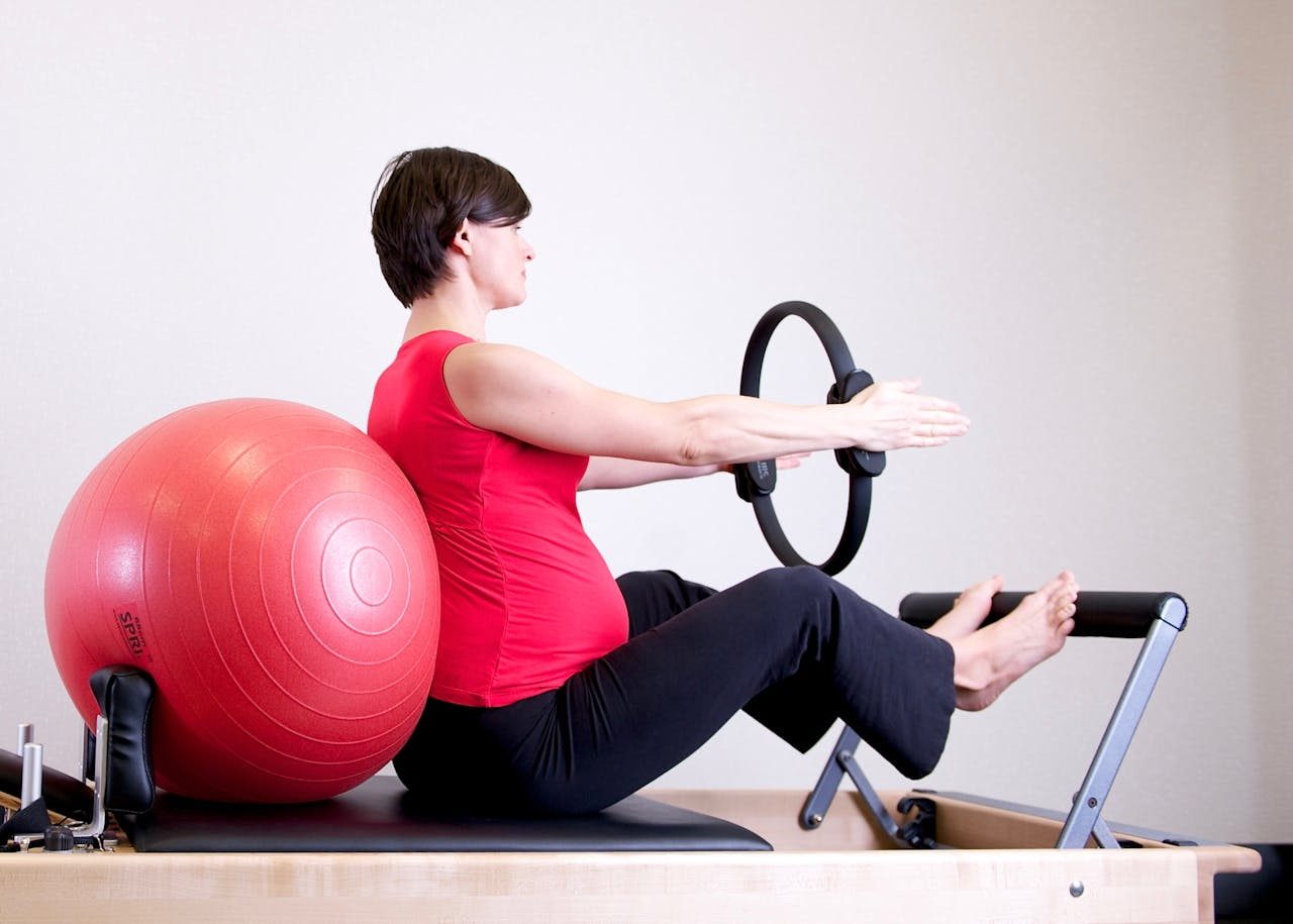 exercices anneau pilates : une femme sur un reformer tient un anneau